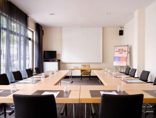 a conference room with tables and chairs and a whiteboard at Flemings Hotel München-Schwabing in Munich
