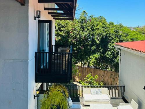 a balcony of a house with a door and a fence at Bliss in the Bay Guesthouse in Plettenberg Bay