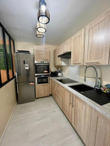 une cuisine avec des armoires en bois et un réfrigérateur en acier inoxydable dans l'établissement Appartement Cosy, à Saint-Gratien