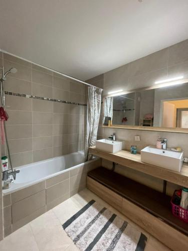 une salle de bain avec deux lavabos et une baignoire dans l'établissement Appartement Cosy, à Saint-Gratien