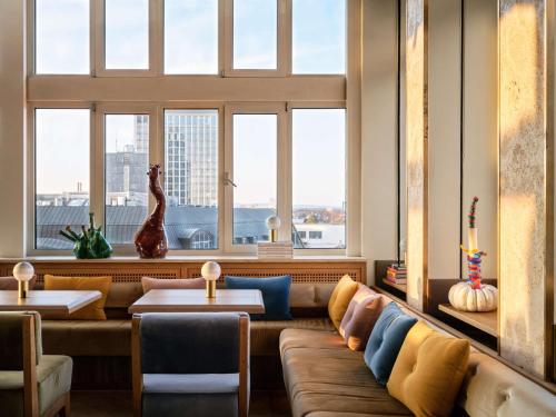 a living room with a couch and two windows at Flemings Selection Hotel Frankfurt-City in Frankfurt/Main
