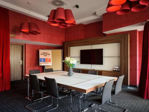 a conference room with a table and chairs and red walls at Flemings Selection Hotel Frankfurt-City in Frankfurt/Main