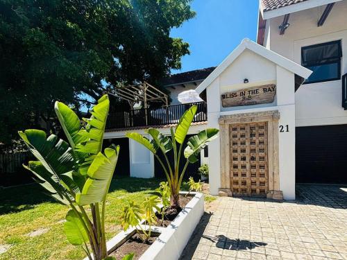 a house with a sign that reads kiss of the bark at Bliss in the Bay Guesthouse in Plettenberg Bay