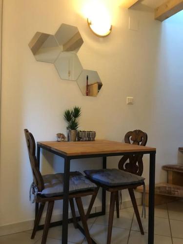 une table à manger avec deux chaises et une horloge dans l'établissement Studio de charme à Niederbronn-les-Bains, à Niederbronn-les-Bains