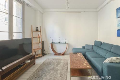 un salon avec un canapé bleu et une télévision dans l'établissement Flexliving - T2 - Servan, à Paris