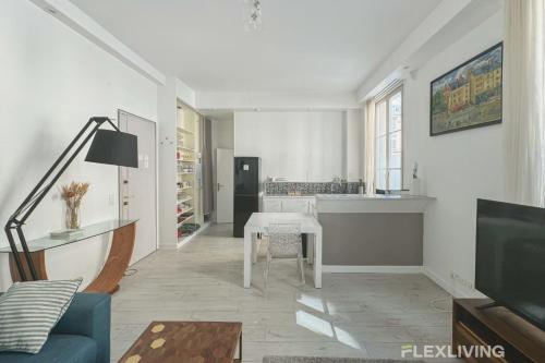 un salon avec une table et une cuisine dans l'établissement Flexliving - T2 - Servan, à Paris