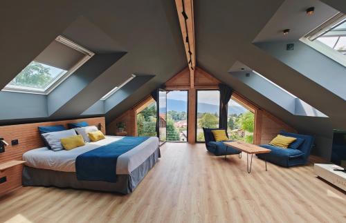 a bedroom with a bed and a couch and windows at La Fruitière de Vérel, logements modulables neufs, calmes, entre lac et montagne, max 11 personnes in Rovagny