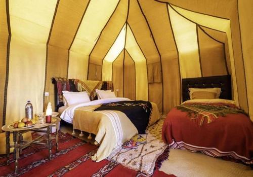 a room with two beds and a table in it at Desert Luxury Tented & Activities in Hassilabied