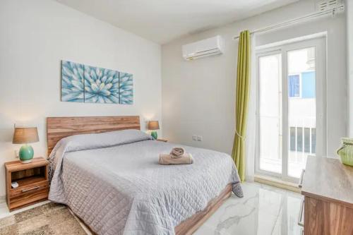 a white bedroom with a bed and a window at Seaview Portside Penthouse SUPERIOR in St Paul's Bay
