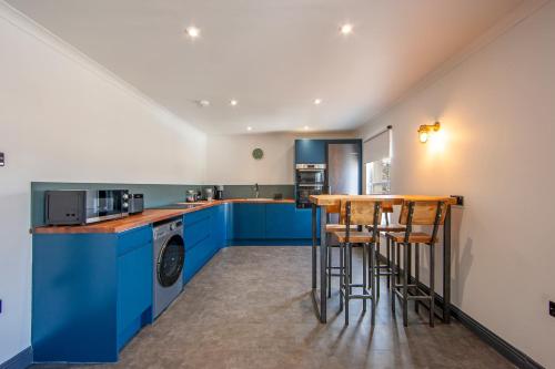 a kitchen with blue cabinets and a bar with stools at Exceptional 2BD Apt - next to ferry & train station in Oban