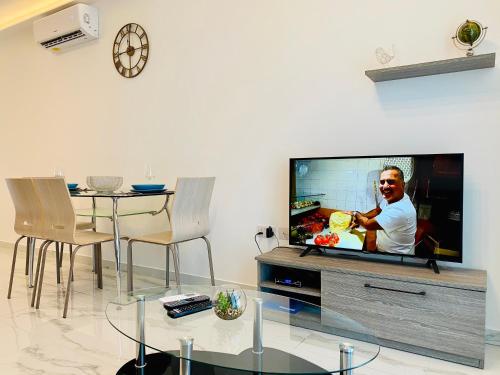 a living room with a tv and a table with chairs at Seaview Portside Penthouse SUPERIOR in St Paul's Bay
