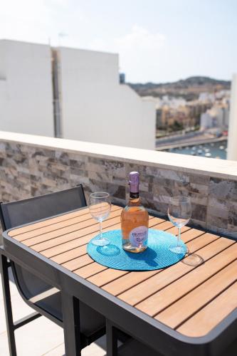 a bottle of alcohol and two glasses on a table at Seaview Portside Penthouse SUPERIOR in St Paul's Bay