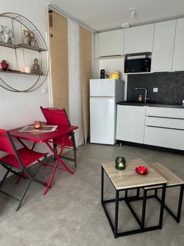 La cuisine est équipée de chaises rouges, d'une table et d'un réfrigérateur. dans l'établissement La Lumière du Coeur, à Saint-Philbert-de-Bouaine