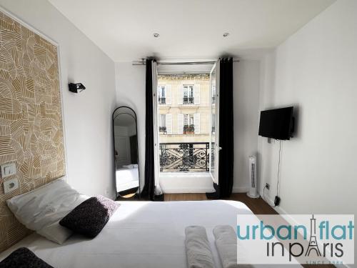 une chambre avec un lit blanc et une grande fenêtre dans l'établissement Urban Flat 18 - Charming 2BDR Parisian Home, à Paris