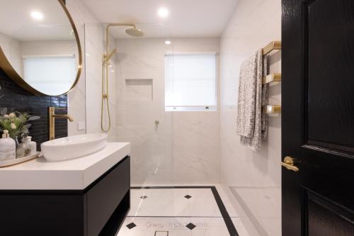 Un baño blanco con lavabo y ducha. en Brisbane Hamilton Hill With Panorama View, en Brisbane