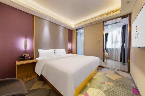 a bedroom with a large white bed and a chair at Yunyuexi Hotel - Guangzhou Baiyun Cengang Branch in Guangzhou
