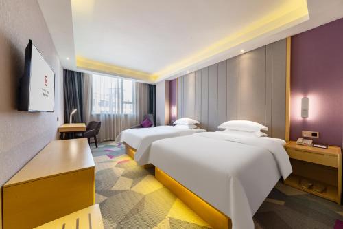 a hotel room with three beds and a television at Yunyuexi Hotel - Guangzhou Baiyun Cengang Branch in Guangzhou