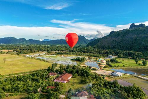 two hot air balloons are flying over a village at Lisha Garden Resort Hotel in Vang Vieng