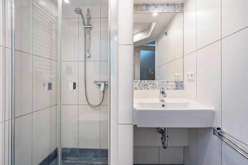 Un baño blanco con lavabo y ducha. en Ferienhaus Kornblume, en Blankenburg