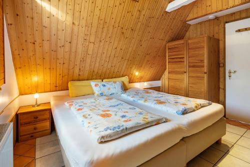 Cama grande en habitación con paredes de madera en Ferienhaus Kornblume, en Blankenburg