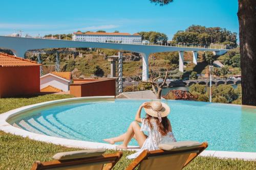 a woman in a hat sitting next to a swimming pool at The Lost Garden in Vila Nova de Gaia