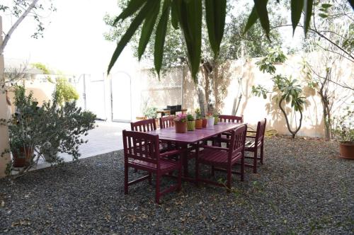迪拜The Villa Jumeirah的一张带椅子和鲜花的木桌