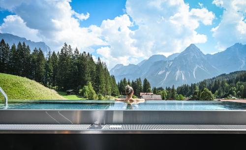 a person in a pool with a view of mountains at Alpen Appartements Lärchenhof in Lermoos