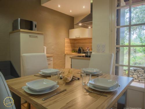 a wooden table with plates and glasses on it in a kitchen at Les Garrigues de la Vallée des Baux in Paradou