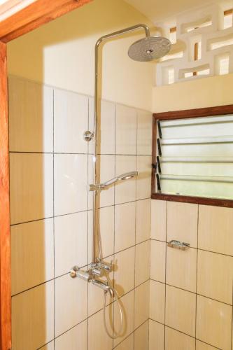 a shower with a shower head in a bathroom at Germano Cottages Garden and Pool in Ukunda