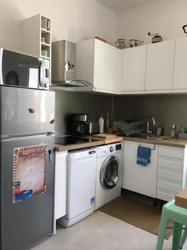 une cuisine avec des armoires blanches et une machine à laver dans l'établissement Cannes congrès, à Cannes