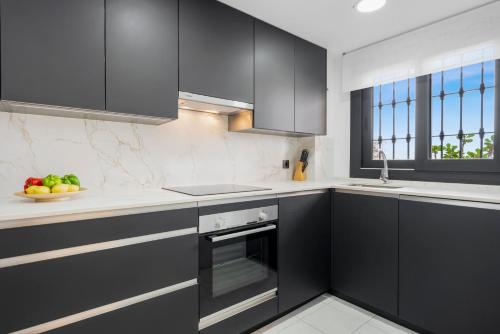 a kitchen with black cabinets and a bowl of fruit at Sky And Sea Estepona Penthouse in Estepona