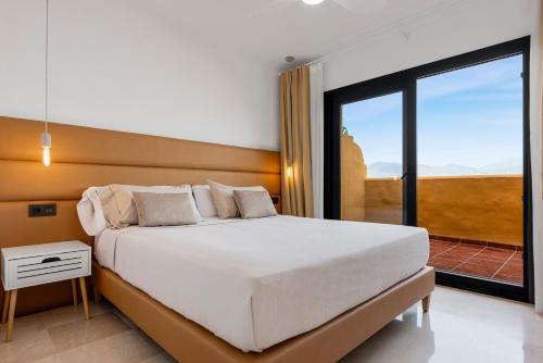 a bedroom with a large white bed and a balcony at Sky And Sea Estepona Penthouse in Estepona