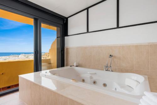 a white bath tub in a bathroom with windows at Sky And Sea Estepona Penthouse in Estepona