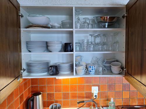 a kitchen cabinet filled with plates and bowls and dishes at Les Collons1800- Bel appart 2pièces-4 pers-piscine-sauna-parking int-Wifi gratuit in Vex