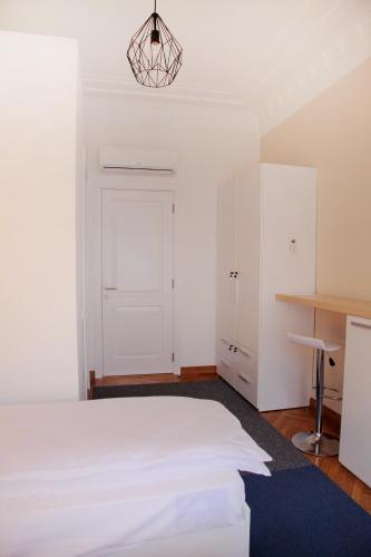 a bedroom with a white bed and a desk at Hostel Karavan Inn in Belgrade