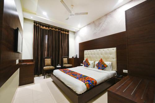 a bedroom with a large bed and a chair in it at FabHotel KK Continental 50 Meter from Railway Station - Amritsar in Amritsar