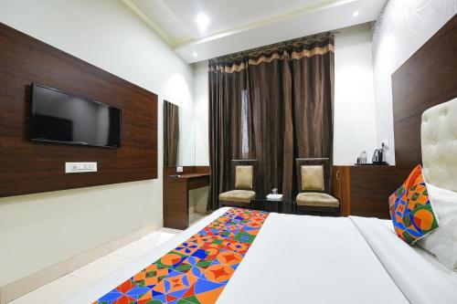 a hotel room with a bed and a flat screen tv at FabHotel KK Continental 50 Meter from Railway Station - Amritsar in Amritsar