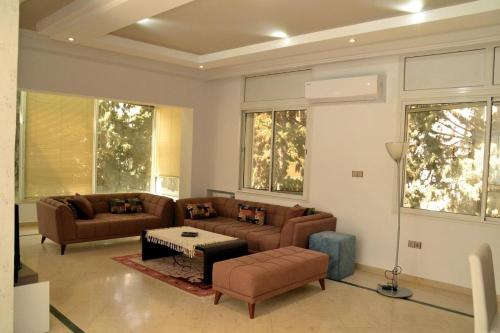 a living room with couches and a table and windows at Superbe appartement au coeur de la Marsa in Tunis