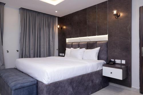 una camera da letto con un grande letto bianco e una panca di House 241 ad Abuja