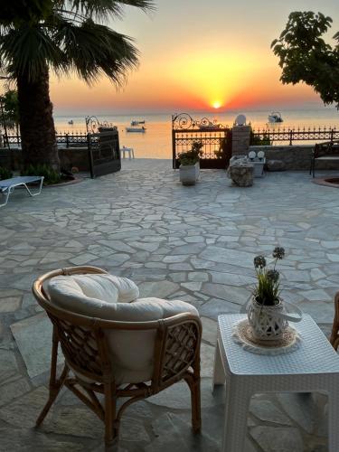 a chair and a table with a sunset in the background at Sea You - Apartments in Avlákia