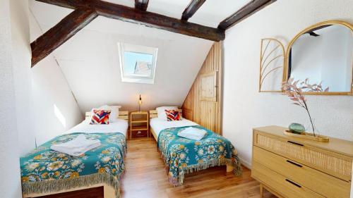 - une chambre mansardée avec 2 lits et un miroir dans l'établissement Le Petit Chez Vous, à Colmar