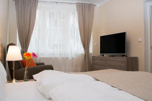 a bedroom with a bed and a flat screen tv at Limes Apartments in Prague