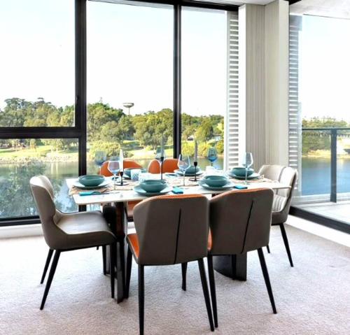 a dining room with a table and chairs and windows at Lakeview Luxury 3Bedrooms Apt Wolli Creek close to Airport CBD in Sydney