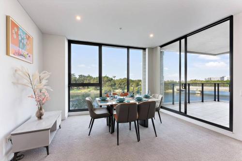 a dining room with a table and chairs and windows at Lakeview Luxury 3Bedrooms Apt Wolli Creek close to Airport CBD in Sydney