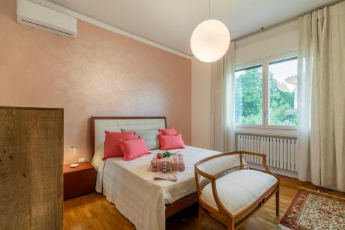 a bedroom with a bed with pink pillows and a chair at Ca' Giorgio - Dolo in Dolo