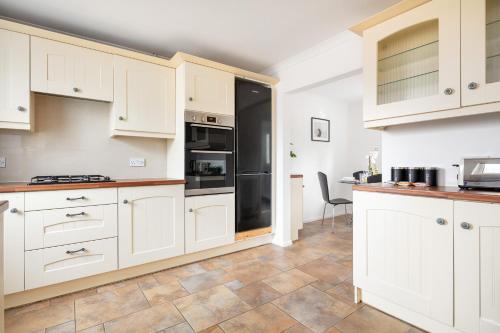 a kitchen with white cabinets and black appliances at Kent Haven - 3 bed house, Games room and Parking in Kent