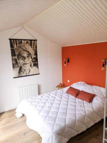 une chambre avec un lit blanc avec un mur orange dans l'établissement Maison au Vieil à 200m de la mer, à Noirmoutier-en-l'lle