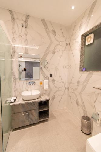 a bathroom with a sink and a marble wall at Hotel Miracle Resort in Phagwāra