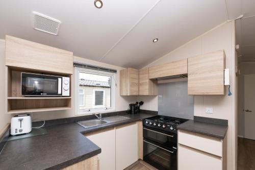 a kitchen with a sink and a stove top oven at Tencreek Holiday Park in Looe