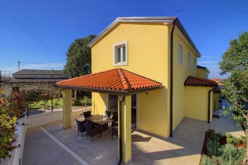 a yellow house with a roof with a table and chairs at Ferienhaus mit Privatpool für 8 Personen ca 120 qm in Mugeba, Istrien Istrische Riviera in Mugeba
